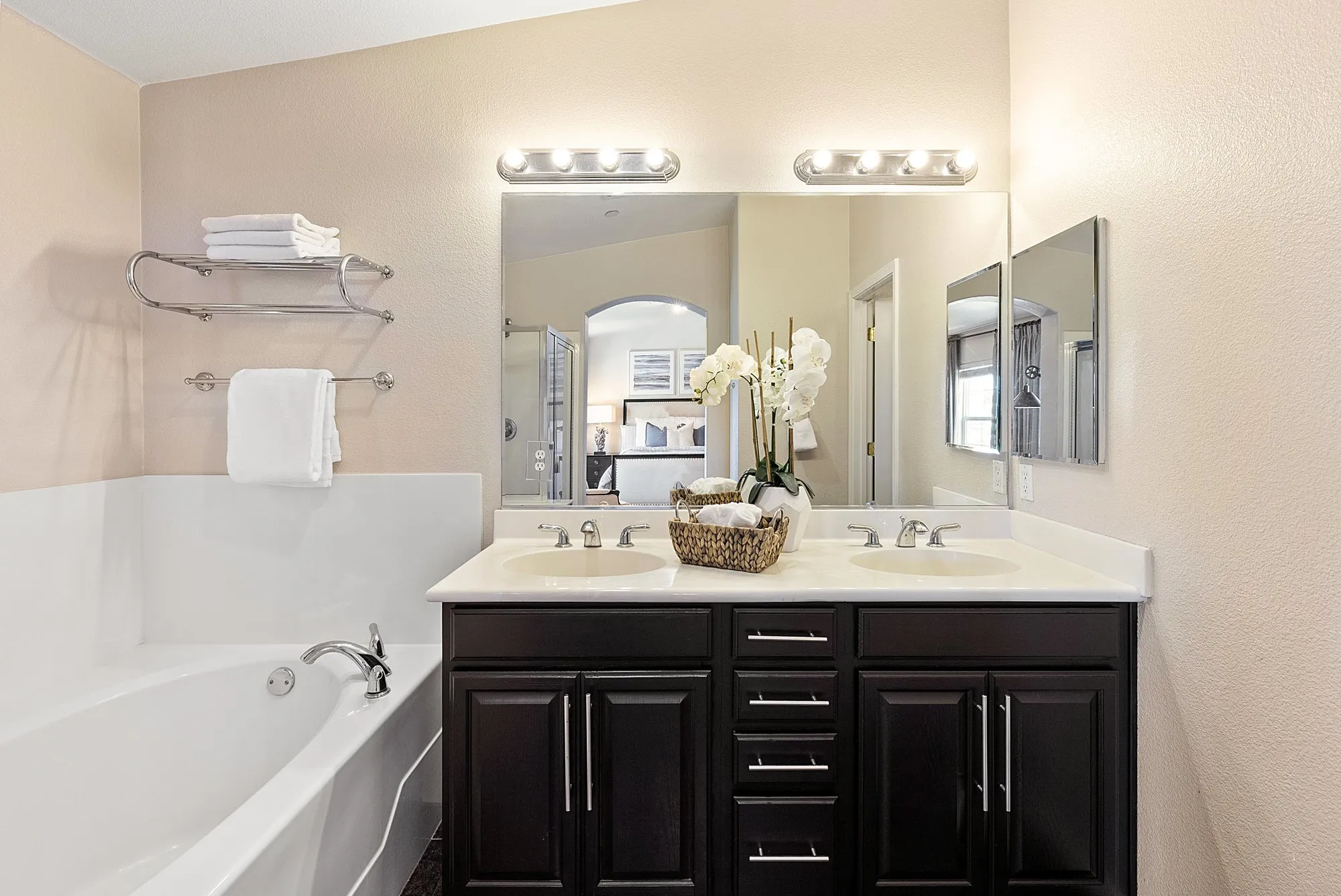A bathroom with a soaking tub, double vanity, and orchids, photographed for a real estate listing